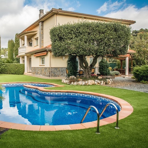 a house and swimming pool surrounded by an artificial turf lawn
